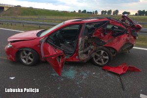 uszkodzony czerwony pojazd na miejscu wypadku