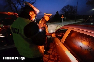 dwóch policjantów przy aucie kontroluje trzeźwość